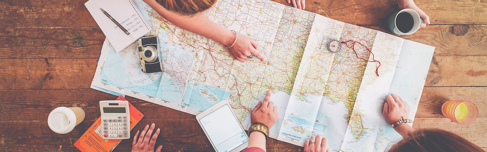 Personer planerar en resa med en karta på ett träbord