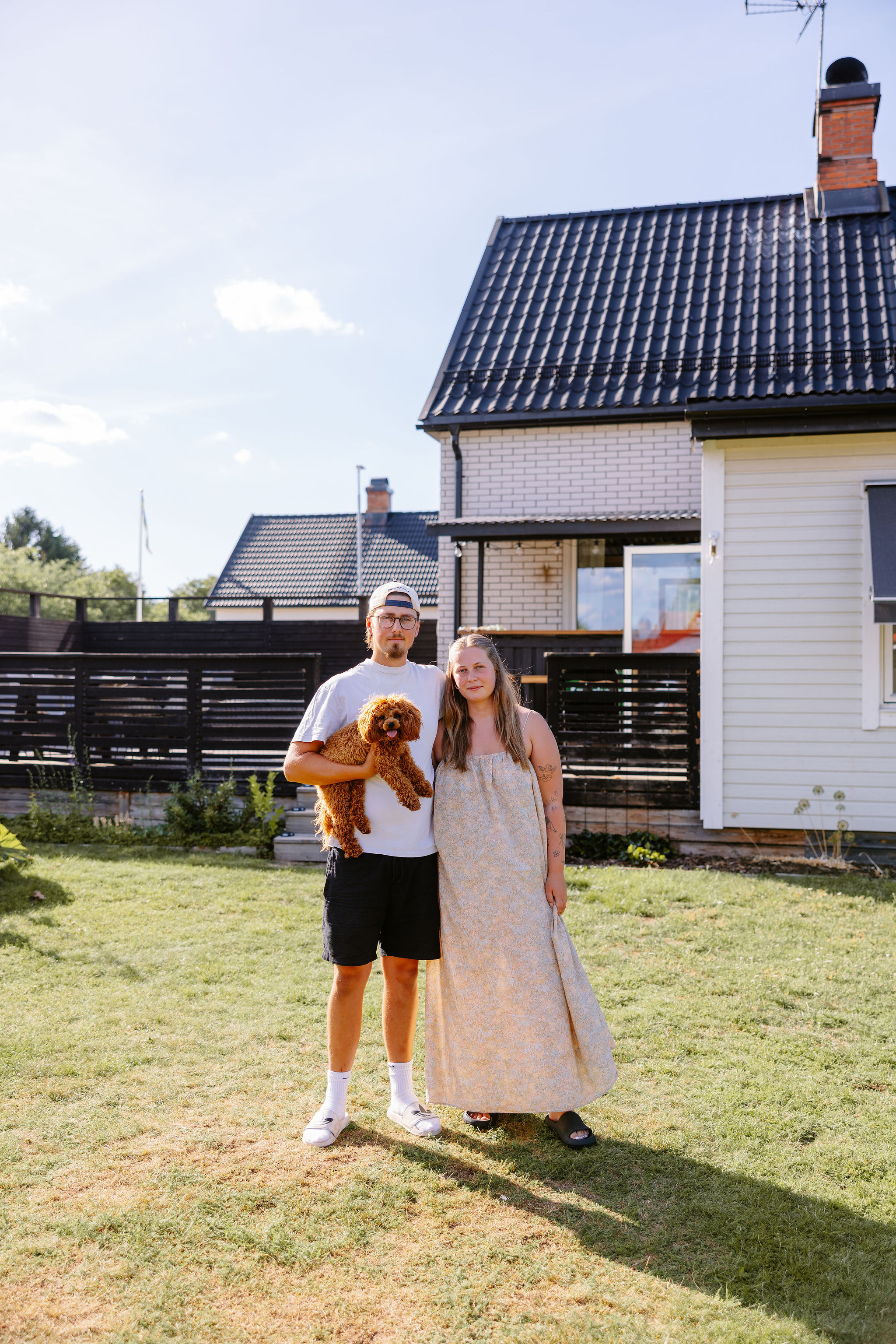 Ett yngre par som står framför sitt hus i Högsby tillsammans med en söt valp